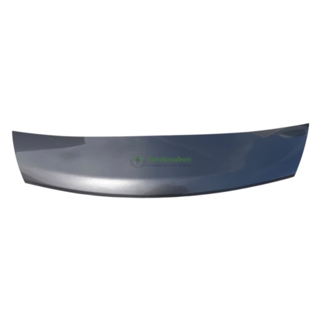 Curved metallic car bumper lip/spoiler part laid on a white background, with light reflections.