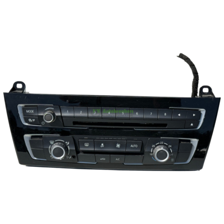 Car dashboard center console with climate control buttons and a rotary knob on the left side and a curved vent strip on top.