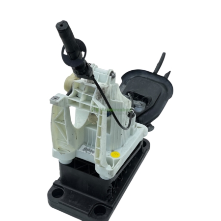 Disassembled car steering column with white plastic housing and black base, exposing wiring and mounting points